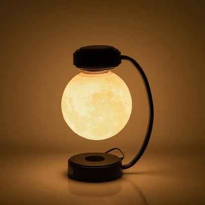 The moon lamp lit warm, floating above its base