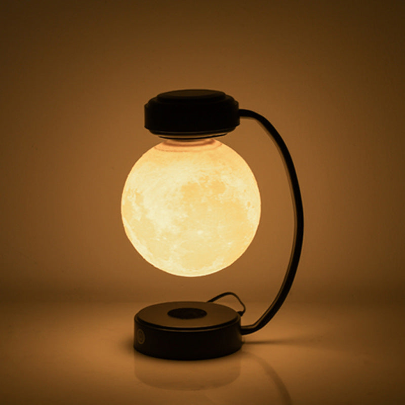 The moon lamp lit warm, floating above its base