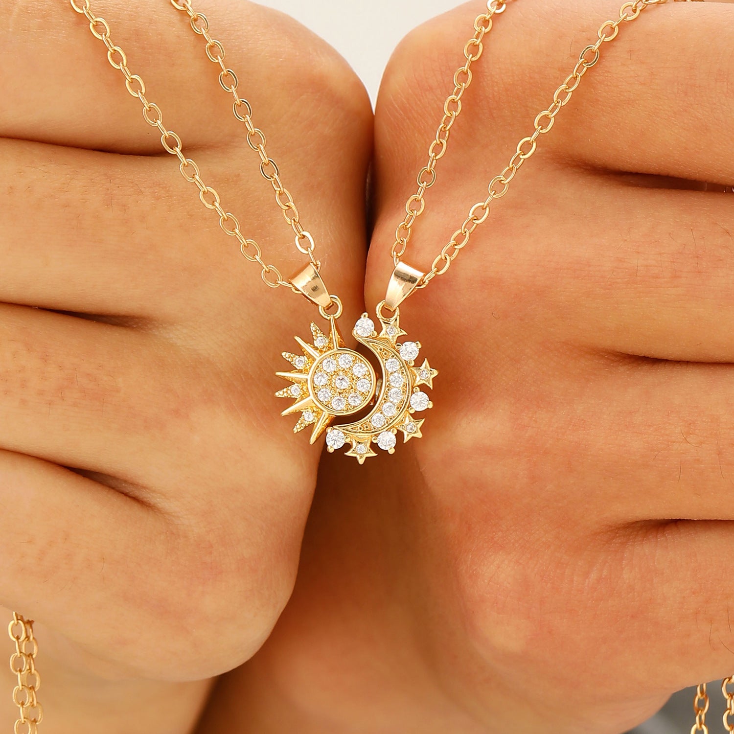 Hands holding the two Éclipse pendants about to click together